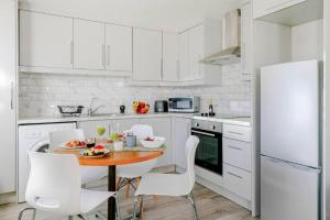 a white kitchen with a table and white chairs at 1-Bed in Bricklane Shoreditch - 5 Sleeps in London