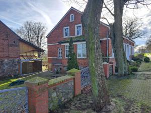 a brick house with a stone wall and a tree at Hof Schumacher in Gumtow