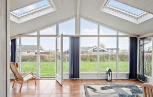 a living room with large windows and a chair at Cozy Home In Sjølund With Sauna in Sjølund