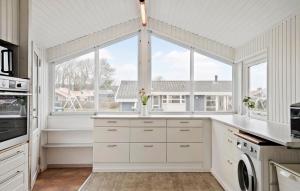 a kitchen with white cabinets and a large window at Cozy Home In Sjølund With Sauna in Sjølund +9 photos