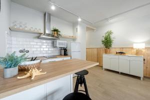 a kitchen with white cabinets and a wooden counter top at Hauzify I Apartament Sunshine Salou in Salou