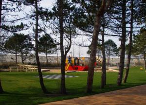 einen Spielplatz mit Spielgeräten in einem Park mit Bäumen in der Unterkunft Gästehaus Achtern Diek - Wohnung 12 in Süderhöft