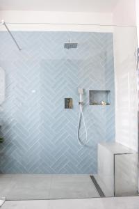y baño con ducha y pared de azulejos azules. en Apartmán v centru, en Šumperk