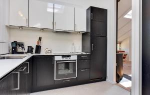 Gorgeous Home In Sydals With Wifi في Sarup: مطبخ مع أجهزة سوداء ودواليب بيضاء