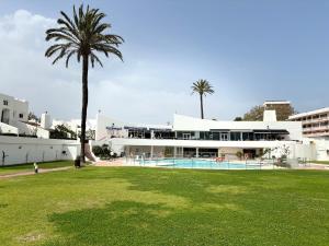 a large white building with a palm tree in front of it at Villacana Community Family Beach Resort in Estepona