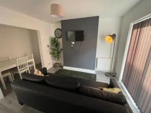 a living room with a black couch and a tv at Suite 3 - Classic Private Room near City Centre in Liverpool