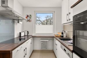 een keuken met witte kasten en een raam bij FREE LIVING - Jungle Design Apartments, Zentrum, Parkplatz, Küche, Wlan in Wolfsburg