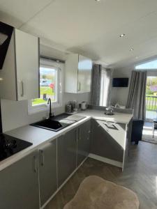 a kitchen with white cabinets and a sink at Modern homely Chalet in Tuxford in Askham