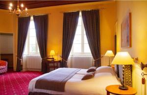 una camera con un grande letto e due finestre di Camping et Hotel Château du Haget a Montesquiou