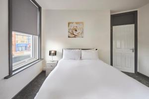 a white bedroom with a large bed and a window at Host & Stay - Clarendon Apartments in Redcar