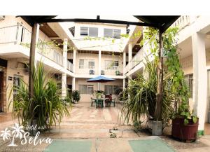 a courtyard of a building with tables and plants at Hotel de la Selva in Leticia