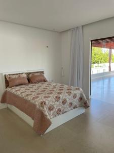 um quarto com uma cama e uma grande janela em Casa de praia em Beberibe em Beberibe