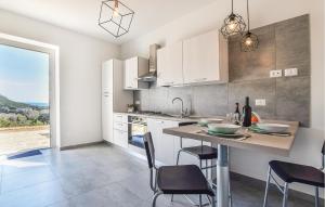 une cuisine avec des placards blancs et une table avec des chaises dans l'établissement Awesome Apartment In Ogliastro Marina With Wifi, à Castellabate