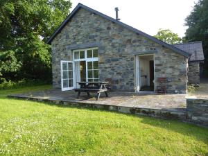 a stone cottage with a picnic table in front of it at Ty Cellin Swyddffynnon in Ystrad-Meurig