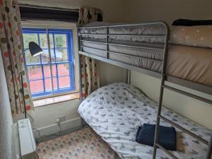 a bedroom with two bunk beds and a window at Bwthyn Heddwch - Peace Cottage in Machynlleth