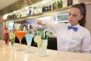 a woman is pouring cocktails at a bar at Canyamel Park Hotel & Spa - 4* Sup - Adults only (+16) in Canyamel