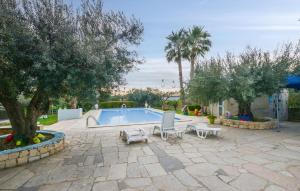 a patio with a swimming pool with two chairs and trees at Awesome Apartment In Comiso With Kitchen in Comiso