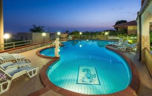 einen großen Pool mit weißen Liegestühlen und Tischen in der Unterkunft Nice Home In Marina Di Ragusa in Marina di Ragusa + 29 Fotos