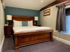 a bedroom with a wooden bed and a window at Best Western Ship Hotel in Weybridge