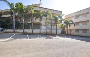 ein Parkplatz vor einem Gebäude mit Palmen in der Unterkunft Lovely Apartment In Marina Di Ragusa in Marina di Ragusa