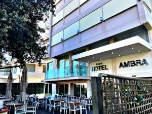 Hotel Ambra في ميلانو ماريتيما: فندق فيه طاولات وكراسي امام مبنى