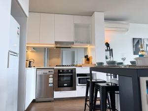布里斯本的住宿－Modern Homely 2BR APT w Parking Bowen Hills，厨房配有白色橱柜和带凳子的台面