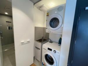a bathroom with a washing machine and a washer at Modern Homely 2BR APT w Parking Bowen Hills in Brisbane