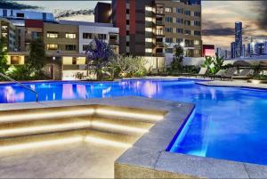 a large swimming pool with blue water in a building at Modern Homely 2BR APT w Parking Bowen Hills in Brisbane