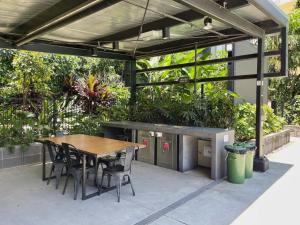 Modern Homely 2BR APT w Parking Bowen Hills في بريزبين: فناء به طاولة وكراسي ونباتات خشبية