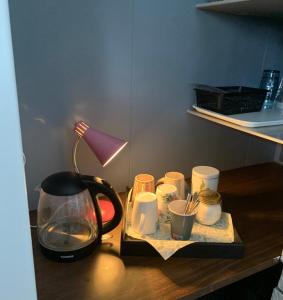 a table with a coffee maker and cups and a lamp at Liten leilighet med to soverom in Valberg +24 photos