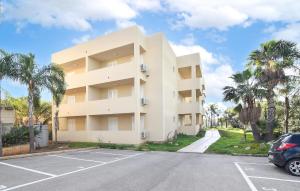 ein großes weißes Gebäude mit Palmen auf einem Parkplatz in der Unterkunft Cozy Apartment In Marina Di Ragusa in Marina di Ragusa