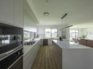 una gran cocina con armarios blancos y una gran isla en Modern Elegance Spacious 5BR Retreat in Rochedale, en Rochedale