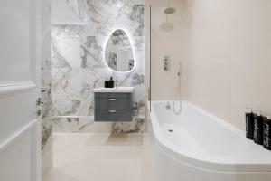 a bathroom with a tub and a sink and a mirror at Luxury 2 Bedrooms Apartment in South Kensington in London