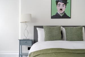 a bed with a painting of a man in a top hat at Luxury 2 Bedrooms Apartment in South Kensington in London
