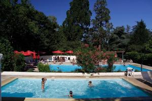 un gruppo di persone che nuotano in piscina di Camping et Hotel Château du Haget a Montesquiou