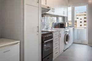 a white kitchen with a sink and a dishwasher at B&B HOTEL e Apartamentos Felgueiras in Felgueiras