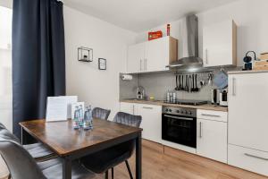 a kitchen with white cabinets and a wooden table at FREE LIVING - City Design Apartments, Zentrum, Outlet, Balkon, Küche in Wolfsburg