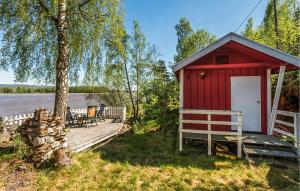 4 Bedroom Cozy Home In Fjerdingby في Hektner: كابينة حمراء مع شرفة بجوار بحيرة