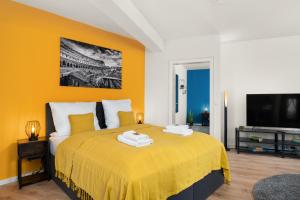 a bedroom with a bed with yellow walls and a tv at FREE LIVING - City Design Apartments, Zentrum, Outlet, Balkon, Küche in Wolfsburg