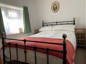 a bedroom with a large bed with a red blanket at Newfoundland Cottage in Whitechurch