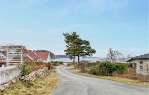 a road with houses and a tree on the side at Lovely Home In Spangereid With Kitchen in Spangereid