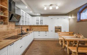a kitchen with white cabinets and a wooden table at Gorgeous Home In Poronin With Wi-fi in Poronin