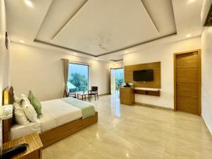 a bedroom with a bed and a flat screen tv at The White Oak Corbett Spa & Resort in Rāmnagar