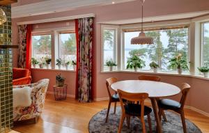 a dining room with a table and chairs and windows at Nice Home In Alingss With Lake View in Alingsås