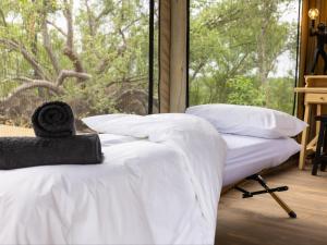 a bedroom with a bed with white sheets and a window at Bushveld Bivouac Private Camp in Mica