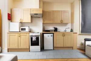 a kitchen with white appliances and wooden cabinets at Very Large Studio on Finchley Road 11 in London