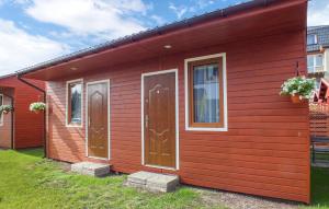 a red house with two doors and two windows at Pet Friendly Home In Miedzyzdroje With Kitchen in Międzyzdroje