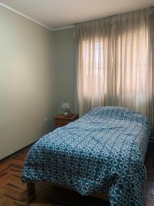 a bedroom with a bed with a blue comforter and a window at Habitación doble in Pisco