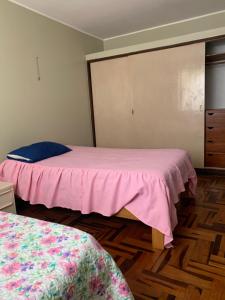 1 dormitorio con 2 camas con sábanas rosas y vestidor en Habitación doble, en Pisco