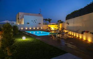 einen Hinterhof mit Pool in der Nacht in der Unterkunft Cozy Home In Marina Di Ragusa With Wifi in Marina di Ragusa